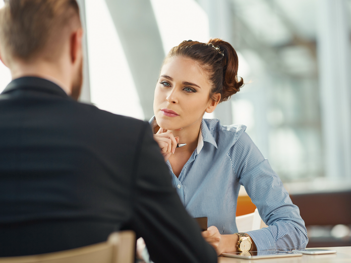 Homem e mulher frente a frente em contexto corporativo realizando uma entrevista de emprego.