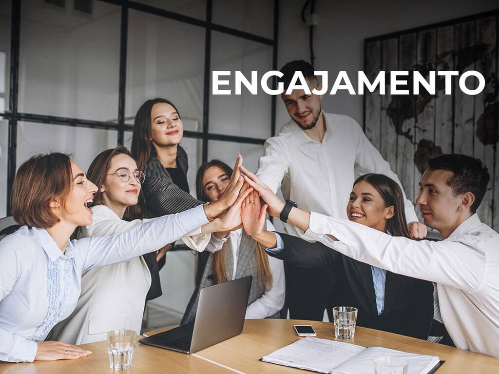 Foto de uma equipe unindo as mãos e representando o engajamento.